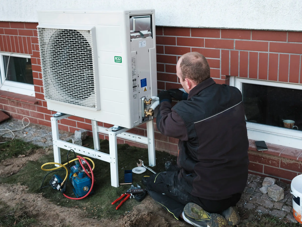 monteur gehurkt naast warmtepomp tijdens montage